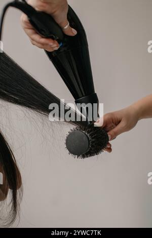 Nahaufnahme einer Friseurin, die lange Haare einer Frau föhnt Stockfoto