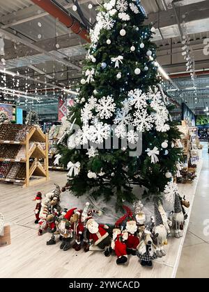 Kiew, Ukraine - 2. Dezember 2024: Ein großer Weihnachtsbaum, der mit Schneeflocken und Ornamenten geschmückt ist. Unter dem Baum gibt es verschiedene Urlaube Stockfoto