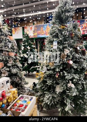 Kiew, Ukraine - 02. Dezember 2024: Künstliche Weihnachtsbäume mit Dekorationen und Ornamenten werden in einem Geschäft ausgestellt, das für die Weihnachtszeit bereit ist. Stockfoto