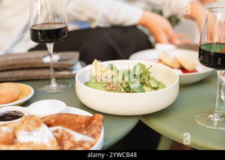 Nahaufnahme eines Salats mit Avocado, Salat, Gurke und Sonnenblumen auf einem Kaffeetisch mit Brot und Rotwein Stockfoto