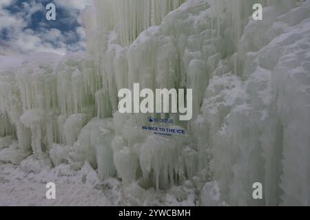 Eine Mauer aus gefrorenem Eis und Eiszapfen ragt über den Himmel mit einem humorvollen Schild in Ice Castles im Genfer See, Wisconsin, USA Stockfoto
