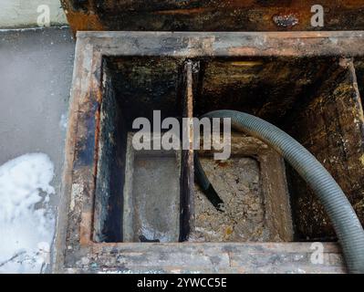 Müllabfuhr aus der Kanalisation. Entfernen von Schlamm und Schlamm durch Pumpschlauch. Stockfoto