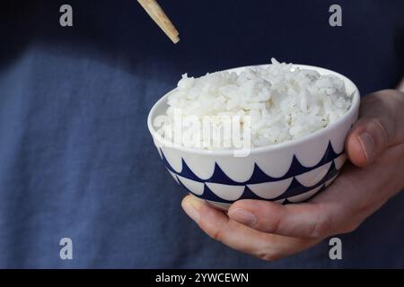 Nahaufnahme von Kaukasiens Hand, die eine Schüssel mit gekochtem weißem Reis hält. Stockfoto