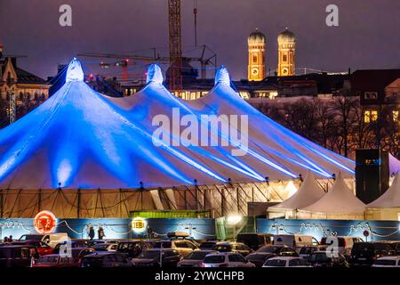 Tollwood Winterfestival auf der Theresienwiese, Münchner Wahrzeichen Frauenkirche, München, Dezember 2024 Deutschland, München, Dezember 2024, das Tollwood Winterfestival leuchtet aus dem Dunkeln des Abends, Münchner Wahrzeichen Frauenkirche, Theresienwiese, farbig angestrahlte Zelte, das Winter-Tollwood geht vom 26. Dezember. November bis 22. November. Dezember 2024, Winter, Kultur, Weihnachtszeit, Veranstaltung, *** Tollwood Winter Festival auf der Theresienwiese, Münchner Wahrzeichen Frauenkirche, München, Dezember 2024 Deutschland, München, im Dezember 2024 erstrahlt das Tollwood Winter Festival im Dunkeln des Abends. Stockfoto