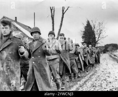 Gefangener amerikanischer G.I. in der Schlacht der Bulge amerikanische Kriegsgefangene marschieren entlang der Straße an der Westfront. Deutscher Film aufgenommen. Stockfoto