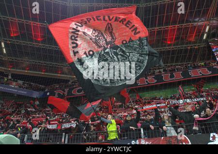 Leverkusen, Nordrhein-Westfalen, Deutschland. Dezember 2024. Ein Bayer-Leverkusen-Fan schwingt eine Flagge und andere halten Schals hoch, bevor am 6. Spieltag der UEFA Champions League zwischen Bayer Leverkusen und Inter Mailand in der BayArena in Leverkusen am 10. Dezember 2024 in die Höhe getrieben wurde. (Kreditbild: © Kai Dambach/ZUMA Press Wire) NUR REDAKTIONELLE VERWENDUNG! Nicht für kommerzielle ZWECKE! Stockfoto