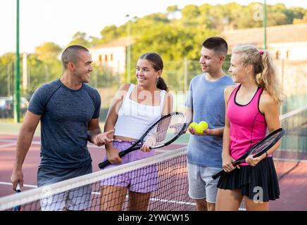 Zwei Tennisspielerpaare diskutieren gern über ein vergangenes Spiel auf einem offenen Platz Stockfoto