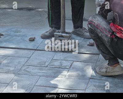 Pattaya, Thailand, geschickte Handwerker arbeiten an einer beeindruckenden Stanzbeton-Oberfläche. Die komplizierten Muster und Texturen erwachen unter ihren fachkundigen Händen zum Leben. Stockfoto