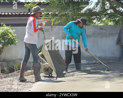 Pattaya, Thailand am 29. November 2024 arbeiten zwei Arbeiter fleißig zusammen, um eine beeindruckende Stanzbeton-Oberfläche in einer lebendigen Atmosphäre zu schaffen, während sie den Beton präzise verlegen. Stockfoto