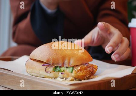 Ein köstliches knuspriges Chicken Sandwich, serviert auf einem rustikalen Holztisch Stockfoto