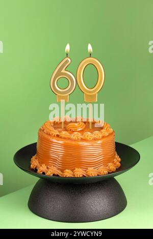 Köstlicher Kuchen mit Dulce de leche - Geburtstagskerze Nr. 60 auf grünem Hintergrund. Stockfoto