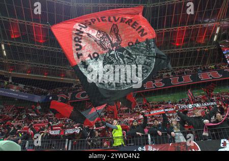 Leverkusen, Nordrhein-Westfalen, Deutschland. Dezember 2024. Ein Bayer-Leverkusen-Fan schwingt eine Flagge und andere halten Schals hoch, bevor am 6. Spieltag der UEFA Champions League zwischen Bayer Leverkusen und Inter Mailand in der BayArena in Leverkusen am 10. Dezember 2024 in die Höhe getrieben wurde. (Kreditbild: © Kai Dambach/ZUMA Press Wire) NUR REDAKTIONELLE VERWENDUNG! Nicht für kommerzielle ZWECKE! Stockfoto