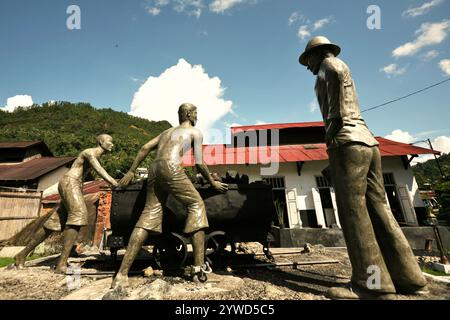 Skulpturen, die einen Aufseher zeigen, der Arbeiter beim Transport von Kohle mit einem Eisenbahnwagen in Sawahlunto, einer ehemaligen Kohlebergbaustadt in Sumatra, aufmerksam macht. Stockfoto