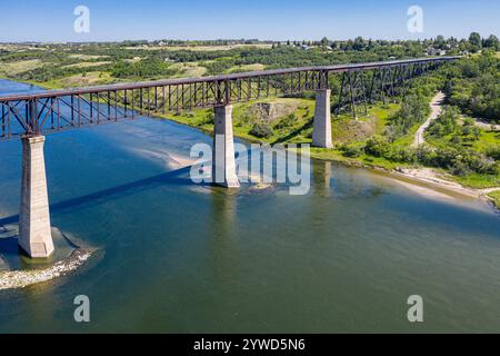 Eine Brücke überspannt einen Fluss mit Blick auf das Wasser darunter. Die Brücke ist alt und verrostet, aber sie ist immer noch stark. Der Himmel ist klar und blau, und das W Stockfoto
