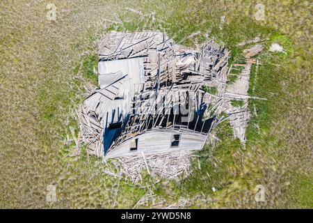 Ein großes, baufälliges Haus befindet sich auf einem Grasfeld. Das Haus ist in einem Zustand des Verfalls, mit kaputten Fenstern und einem zerbröckelnden Dach. Das umgebende A Stockfoto