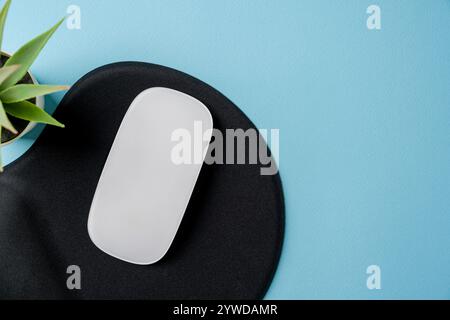 Draufsicht der modernen weißen Maus auf schwarzem Mauspad auf blauem Tisch Stockfoto