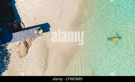 Goldener Sand und azurblaues Wasser bilden einen perfekten Rückzugsort auf Koh Munnork Island. Das Sonnenlicht schimmert, während sich die Besucher am Strand entspannen und im ruhigen Meer unter der warmen Sonne Thailands schwimmen. Stockfoto