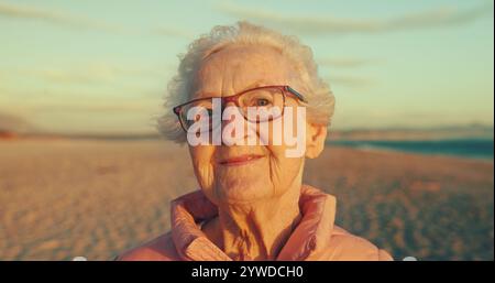 Glücklich, Strand und Porträt einer älteren Frau mit Lächeln für Sommer, Reise und Wochenende in Australien. Vormittag, Sonnenaufgang und Gesicht einer Seniorin auf dem Meer Stockfoto