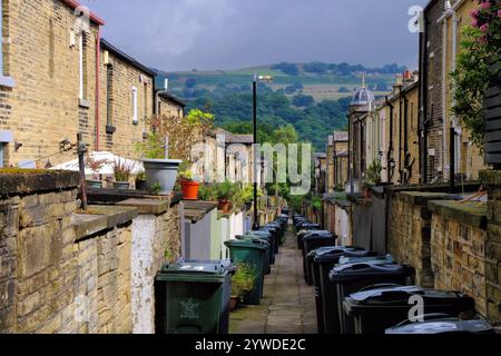 Saltaire: Blick auf die Hügel entlang der Gasse mit Hütten, Gärten und Mülltonnen im viktorianischen Modelldorf Saltaire, Shipley, Yorkshire, England, Großbritannien Stockfoto