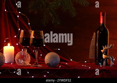 Rotwein, Weihnachtsbeleuchtung und Ornamente auf dem Tisch. Leerzeichen für Text Stockfoto