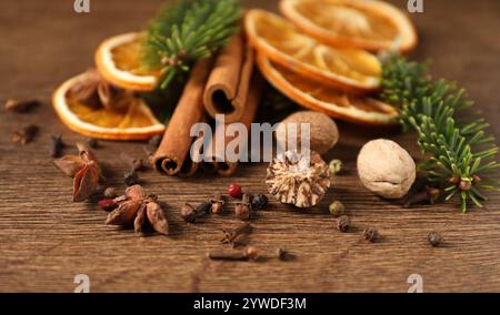 Verschiedene Gewürze, getrocknete Orangenscheiben und Tannenzweige auf Holztisch, Nahaufnahme. Weihnachtszeit Stockfoto
