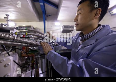 (241211) -- LANZHOU, 11. Dezember 2024 (Xinhua) -- Sun Liangting, ein Forscher am Institut für moderne Physik der Chinesischen Akademie der Wissenschaften, überprüft Ausrüstung am 10. Dezember 2024. Die weltweit erste eigenständige Niedrigenergetik-Schwerionen-Beschleunigeranlage (LEAF), die vom Institut für moderne Physik der Chinesischen Akademie der Wissenschaften entwickelt wurde, hat kürzlich die von der National Natural Science Foundation of China organisierte Sachverständigenprüfung durchlaufen. Das BLATT kann intensive Schwerionenstrahlen und Mischionenstrahlen mit verschiedenen ladezuständen von leichten bis schweren Elementen liefern. Stockfoto