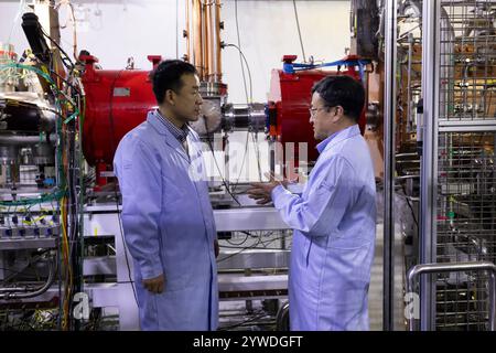 (241211) -- LANZHOU, 11. Dezember 2024 (Xinhua) -- Zhao Hongwei (R), ein Akademiker der Chinesischen Akademie der Wissenschaften (CAS), und Sun Liangting, ein Forscher am Institut für moderne Physik des CAS, diskutieren am 10. Dezember 2024 über den Fortschritt der Experimente vor der Low-Energy-High-Intensity-Schwerionen-Beschleuniger-Anlage (LEB). Die weltweit erste eigenständige Niedrigenergetik-Schwerionen-Beschleunigeranlage (LEAF), die vom Institut für moderne Physik der Chinesischen Akademie der Wissenschaften entwickelt wurde, hat kürzlich die von der National Natural SC organisierte Sachverständigenprüfung durchlaufen Stockfoto