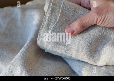 Rolle eines groben Hanftuchs in der Hand einer Frau. Steigende Nachfrage nach Hanfprodukten. Nahaufnahme. Stockfoto