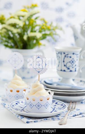 Raffinierte Einrichtung mit dekorierten Cupcakes, feinem porzellan mit Blumenmustern und einer schönen Tischdekoration. Stockfoto