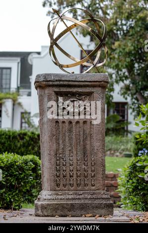 Große armillarische Sonnenuhr aus Messing oder Bronze mit erhöhten römischen Ziffern und Pfeil auf Sockel, Steinsockel mit Muster. Hinterhof Stockfoto