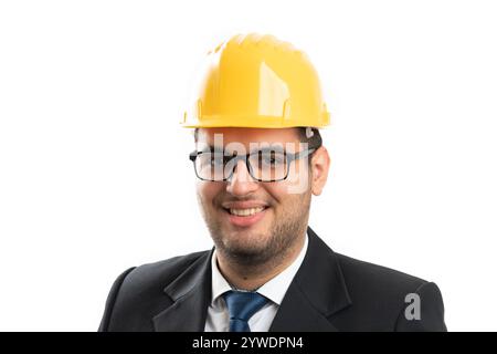 Nahaufnahme eines männlichen Architekten oder Ingenieurs, der mit freundlichem Ausdruck lächelt und einen gelben Schutzhelm für Sicherheit trägt, sowie einen lässigen Anzug auf weißem B Stockfoto