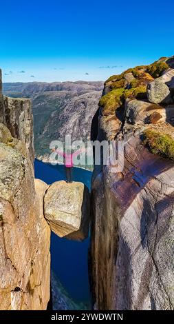 Ein einsamer Wanderer steht am Rande der Kjeragbolten, Norwegen Klippe in Norwegen und genießt den atemberaubenden Blick auf den Fjord darunter. Asiatische Frauen besuchen Kjeragbo Stockfoto