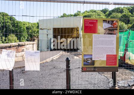 Ironbridge, Shropshire, Großbritannien, 22-06-2018. Die ikonische Brücke wurde während der Renovierung eingezäunt. Auf einem Poster steht: „Erhaltung unseres Erbes“. Stockfoto