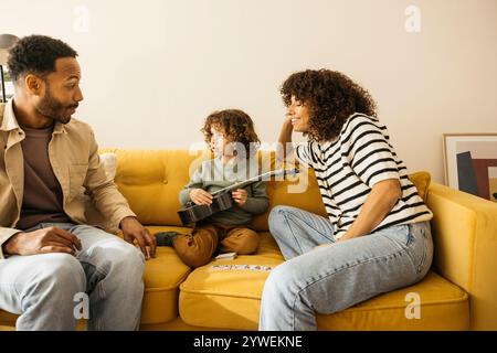 Eine Familie genießt eine gute Zeit zusammen, wenn sie auf einem Sofa sitzt, um sich unterhalten und Musik hören zu können. Stockfoto