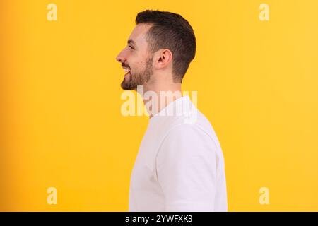 Seitenprofil eines lächelnden Mannes in einem weißen T-Shirt auf gelbem Hintergrund Stockfoto