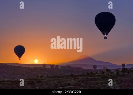 Heißluftballons beim Sonnenaufgang in Kappadokien mit dem Mount Erciyes, Türkei Stockfoto