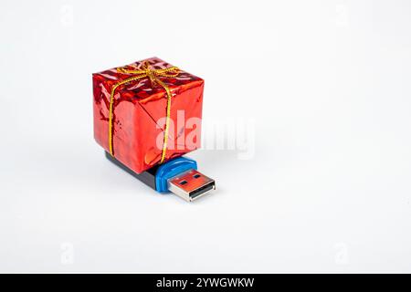 Eingewickelte rote Geschenkbox auf einem usb-Stick, isoliert auf weißem Hintergrund, digitales weihnachtsgeschenk Stockfoto