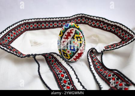 Handgefertigtes osterei mit Perlen. Perlenarbeiten, auf einer rumänischen ethnischen Bluse oder einem Hemd, weiche Nahaufnahme, Stockfoto