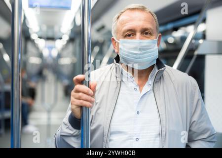 Reifer Passagier mit Schutzmaske fährt in einem U-Bahn-Auto Stockfoto