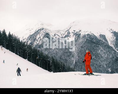 Man Skier steht auf verschneiten Berghängen Stockfoto