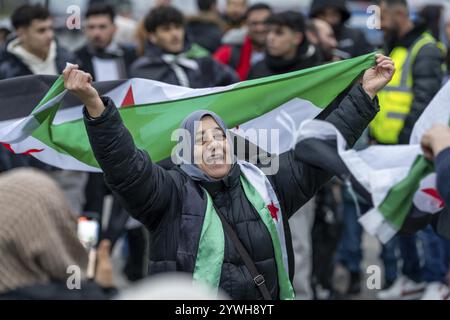 Syrische Frau feiert das Ende des Assad-Regimes nach dem Machtwechsel in Syrien bei einer Kundgebung auf dem Platz vor dem Hauptbahnhof in Stockfoto