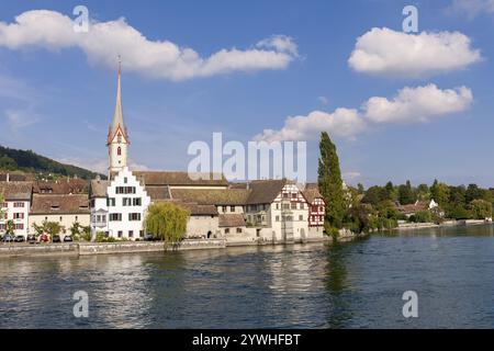 Kirche mit hohem Turm am Flussufer, umgeben von Fachwerkhäusern und Bäumen, Blick auf die Altstadt von Stein am Rhein mit dem Kloster St. Georg Stockfoto