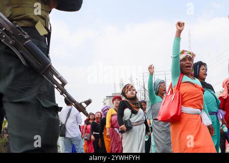 Frauen erheben ihre Stimme vor einer Reihe von Polizeibeamten, während sie während einer Massenkundgebung in Imphal am 10. Dezember 2 mit Schusswaffen bewachen Stockfoto