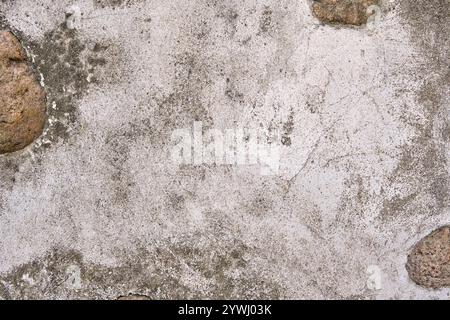 Gerissene Betonwand mit grauer Zementoberfläche. Graue alte Wand mit schäbigem, beschädigtem Putz oder Zement und Backsteinhintergrund eines alten schmutzigen E Stockfoto