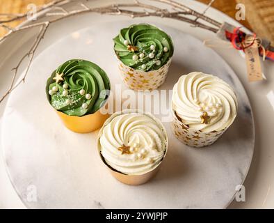 Köstliche Weihnachts-Cupcakes mit festlicher Dekoration auf Marmortablett Stockfoto