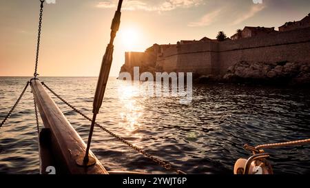 Altes Segelschiff segeln in den Sonnenuntergang neben der Stadtmauer von Dubrovnik Stockfoto