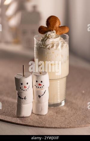 Eierlikör mit Schlagsahne und Lebkuchenmännchen, neben zwei Schneemännern Stockfoto