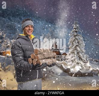 Ein Mann hält einen Haufen Brennholz in einer verschneiten Nacht vor einem Berghaus Stockfoto