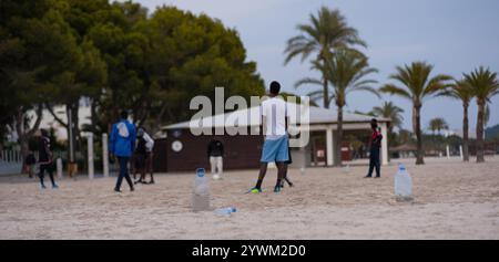 Junge Afroamerikaner spielen Fußball am Strand. Strandfußball mit improvisierten Fußballtoren aus Flaschen. Freizeit junger Männer Stockfoto