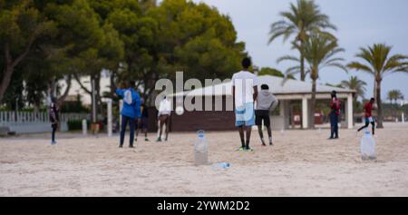Junge Afroamerikaner spielen Fußball am Strand. Strandfußball mit improvisierten Fußballtoren aus Flaschen. Freizeit junger Männer Stockfoto